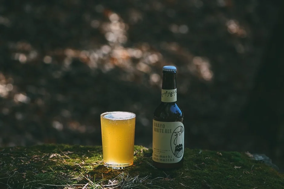 森の中の苔の上に置かれたビールグラスとボトル
